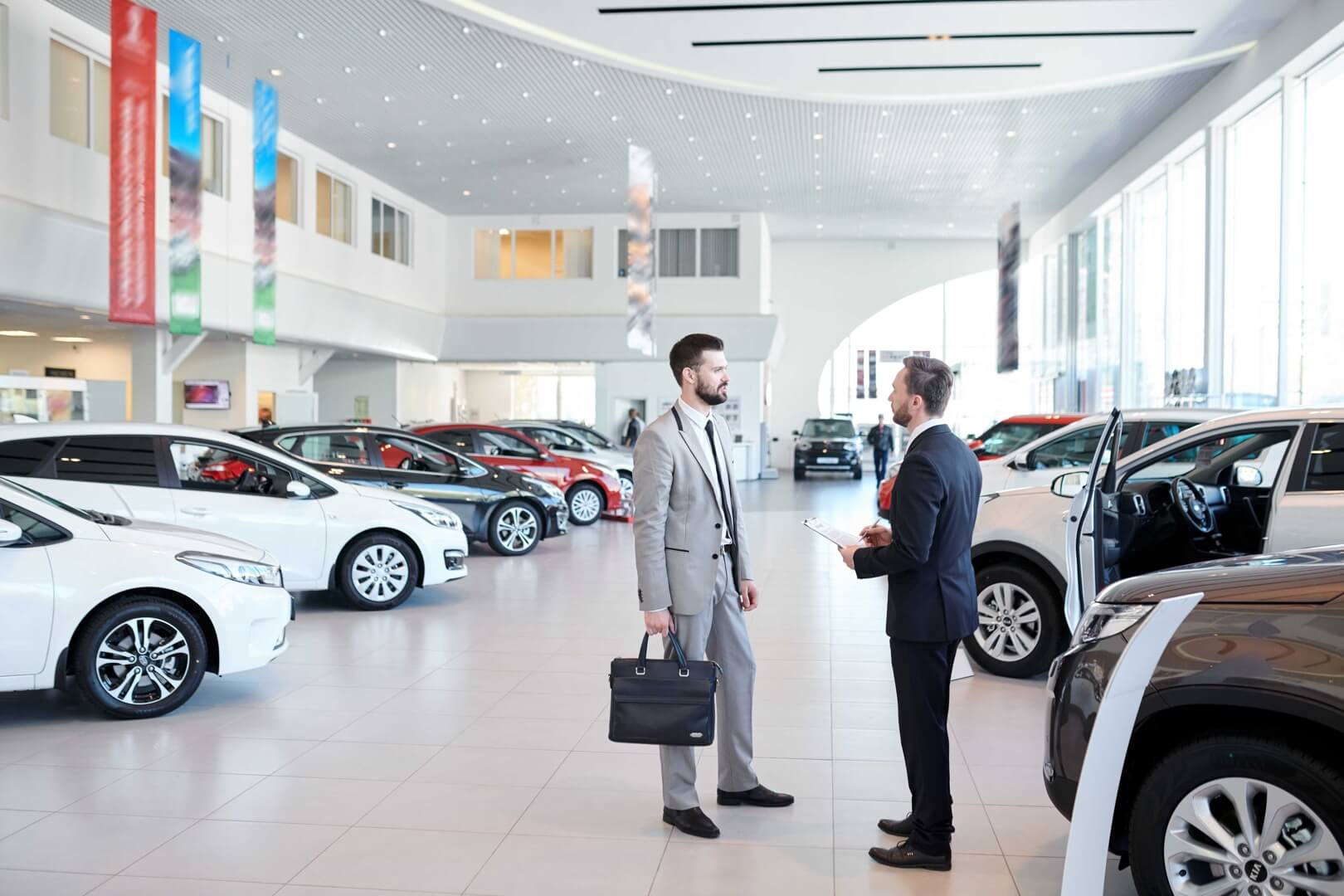 A man and a car dealer discussing inside a car dealership